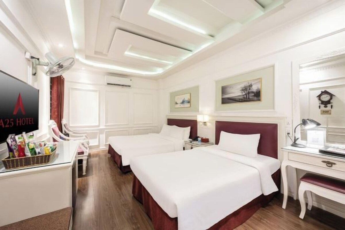Una camera d'albergo con due letti, una scrivania, una sedia, una TV e un minibar.