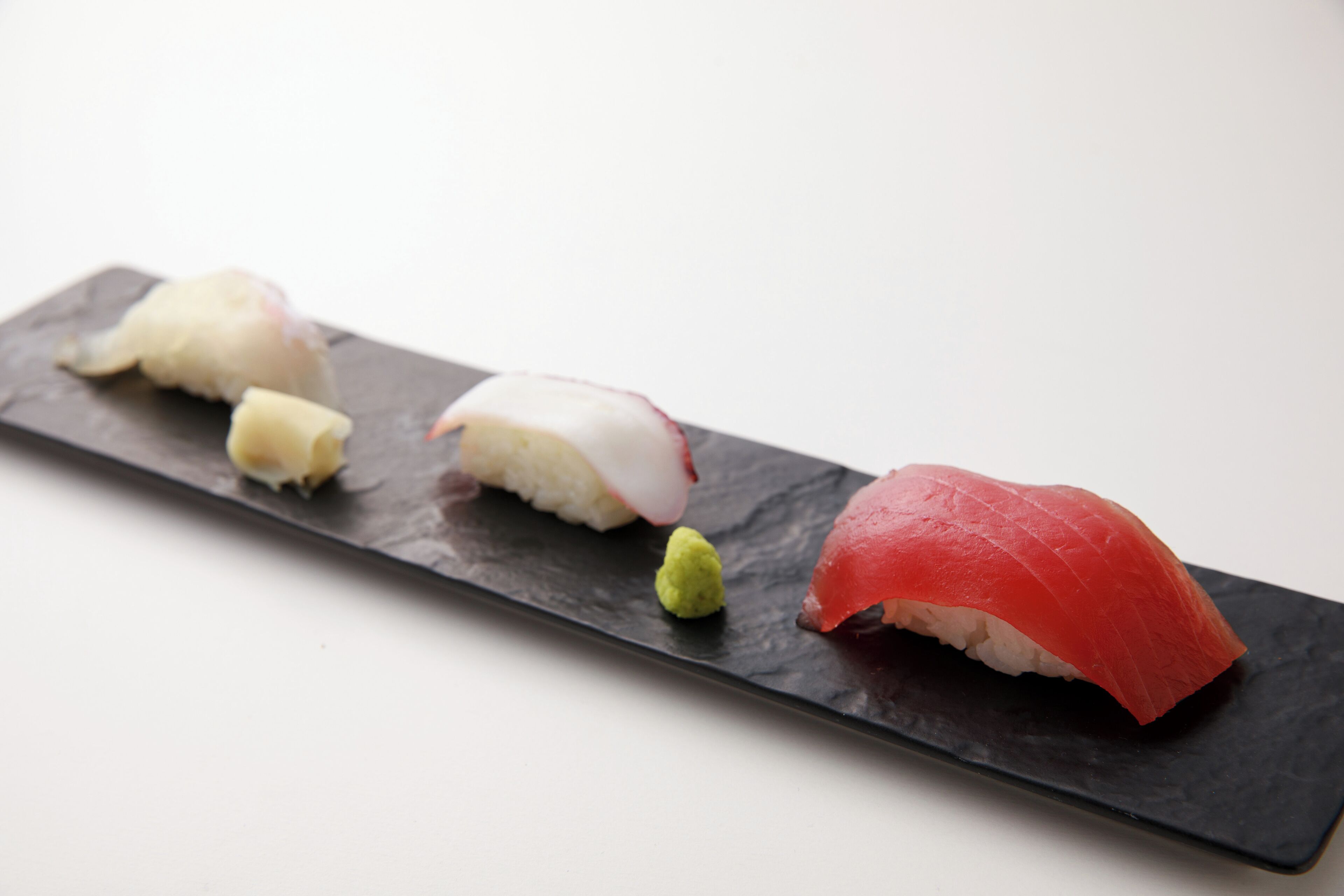 A black rectangular plate with four pieces of sushi.