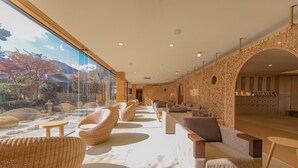 A modern interior with wicker furniture, a large window, and a view of trees and mountains. - Hana Beppu (Beppu)