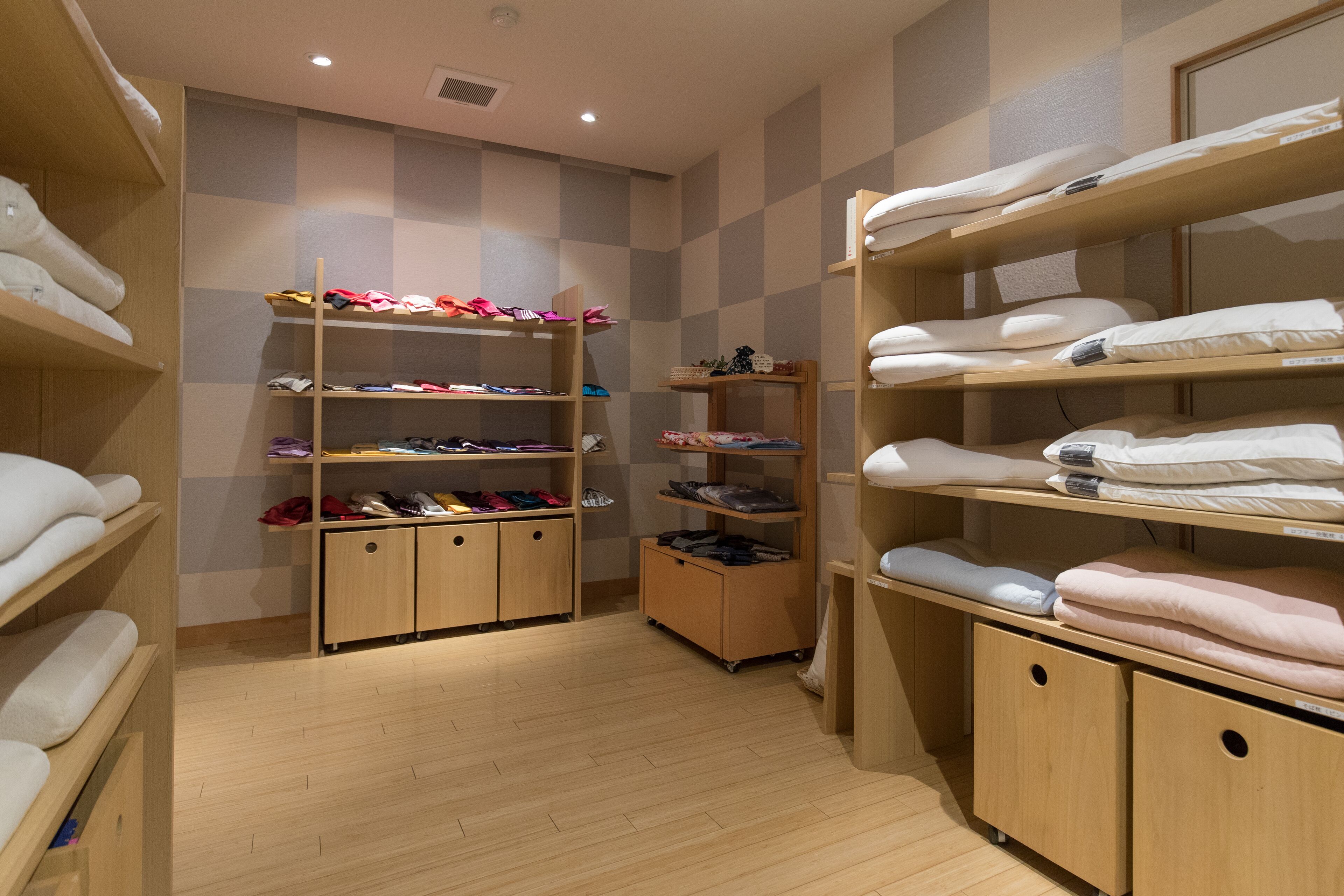 A hotel room with wooden shelves and cabinets, organized with neatly folded towels and clothing.