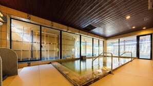 An indoor swimming pool with clear glass walls, wooden ceiling, and tiled floor. - Hana Beppu (Beppu)