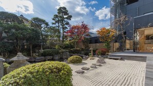 A traditional Japanese garden with a wooden deck, stone lanterns, and various plants. - Hana Beppu (Beppu)