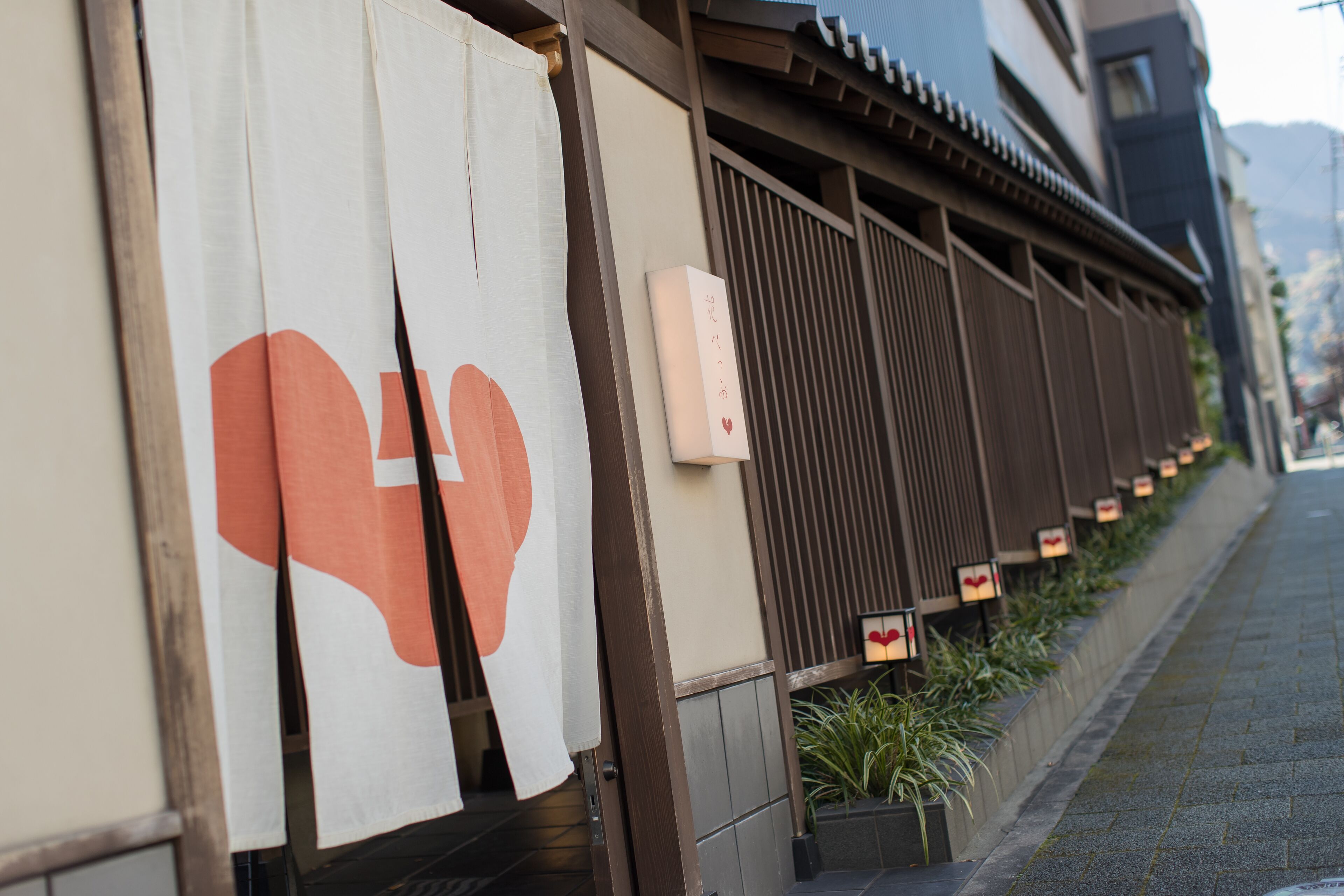 A traditional Japanese building with sliding doors and a small garden area with plants.