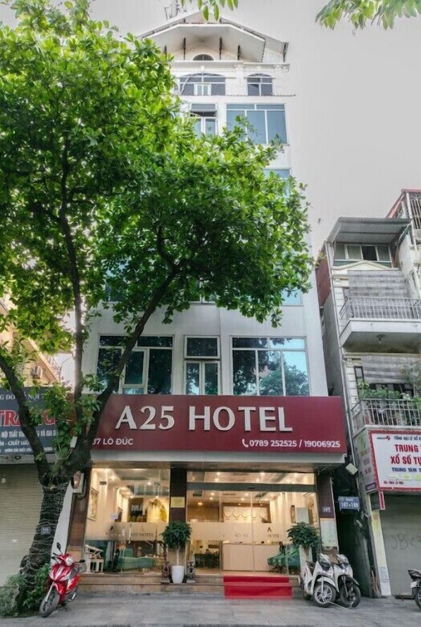 A25 Hotel with a visible entrance, a red carpet, and a tree in front. - A25 Hotel - 185 - 187 Lo Duc (Hanoi)