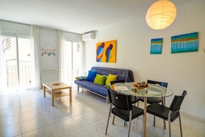 Una sala moderna con un sofá, una mesa de comedor de vidrio y dos cuadros en la pared.