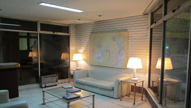 A modern living room with a sofa, coffee table, and lamps. There is a large window and a painting on the wall. - Hotel Royal (Córdoba)