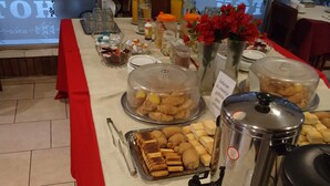 A buffet setup with various food items, including pastries and bread, covered with lids, and a coffee maker. - Hotel Royal (Córdoba)