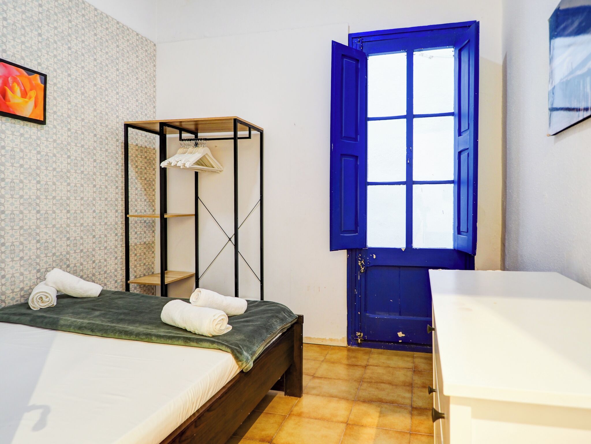 Une chambre à coucher comprenant un lit, une armoire, une fenêtre et un porte-serviettes.
