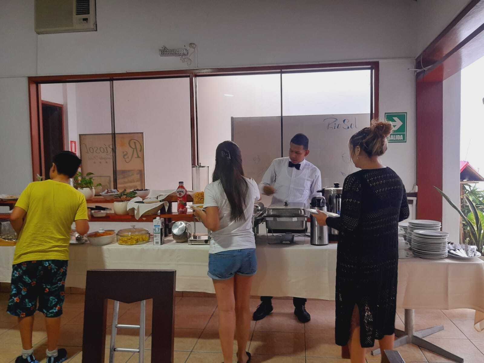 Un groupe de personnes se trouve près d’un buffet équipé d’un comptoir, d’un tableau blanc et d’un panneau indiquant la sortie.