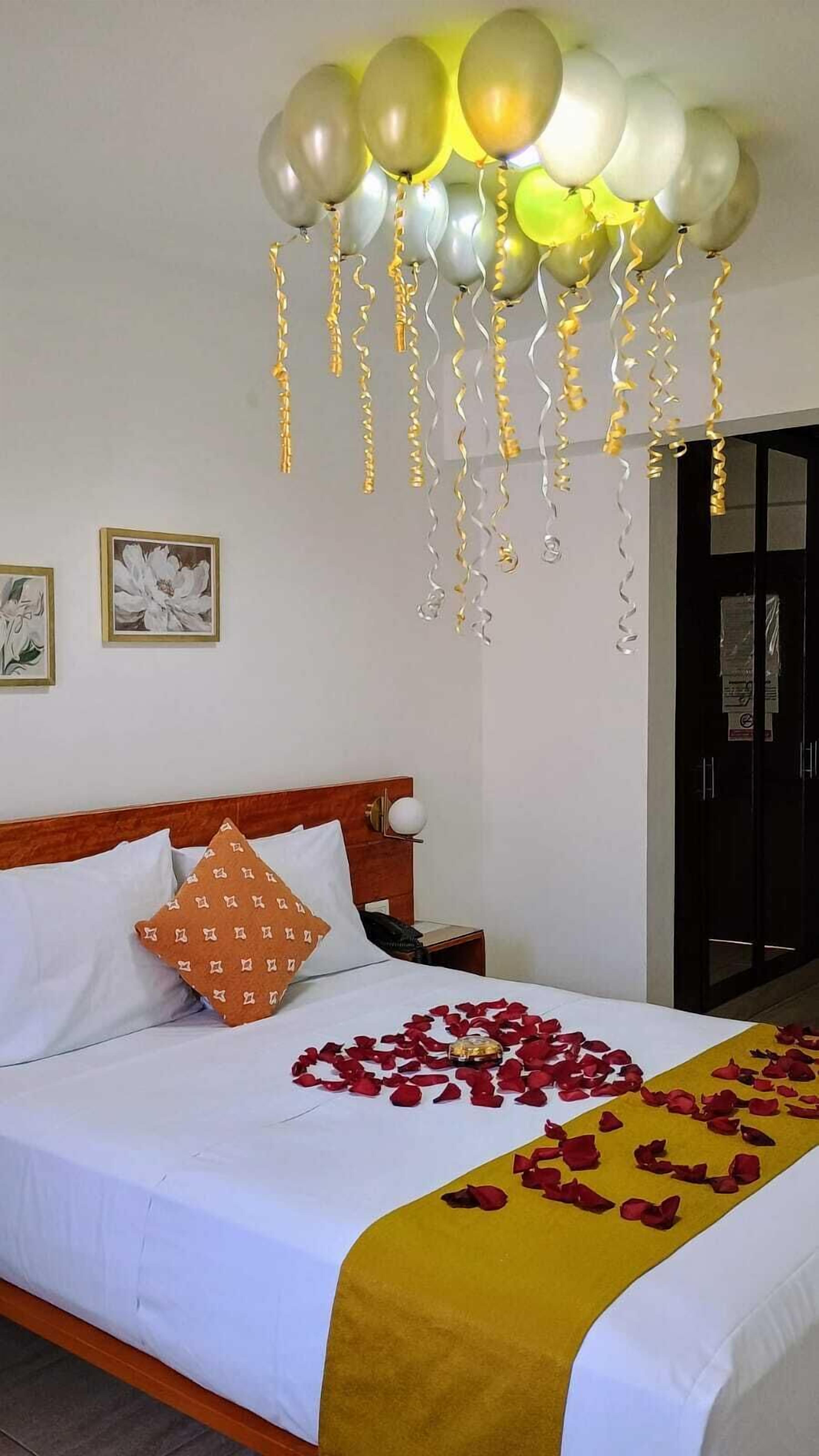Habitación de hotel con cama, mesita de noche, un cuadro en la pared y una puerta con un cartel.