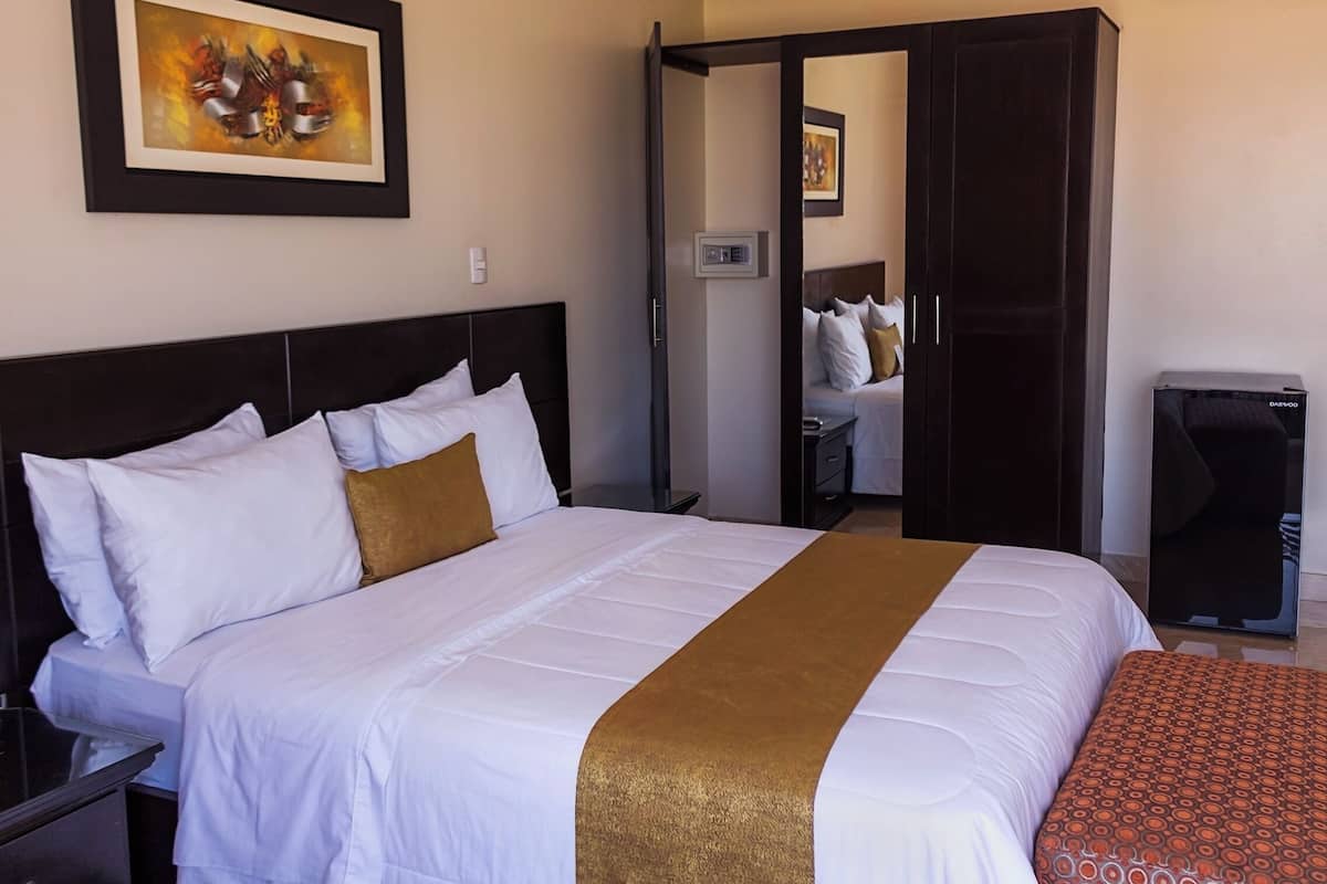 A hotel room with a large bed, a wardrobe, a desk, and a chair.