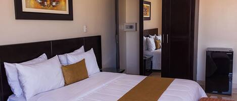 Una habitación de hotel con una cama grande, un armario, un escritorio y una silla.