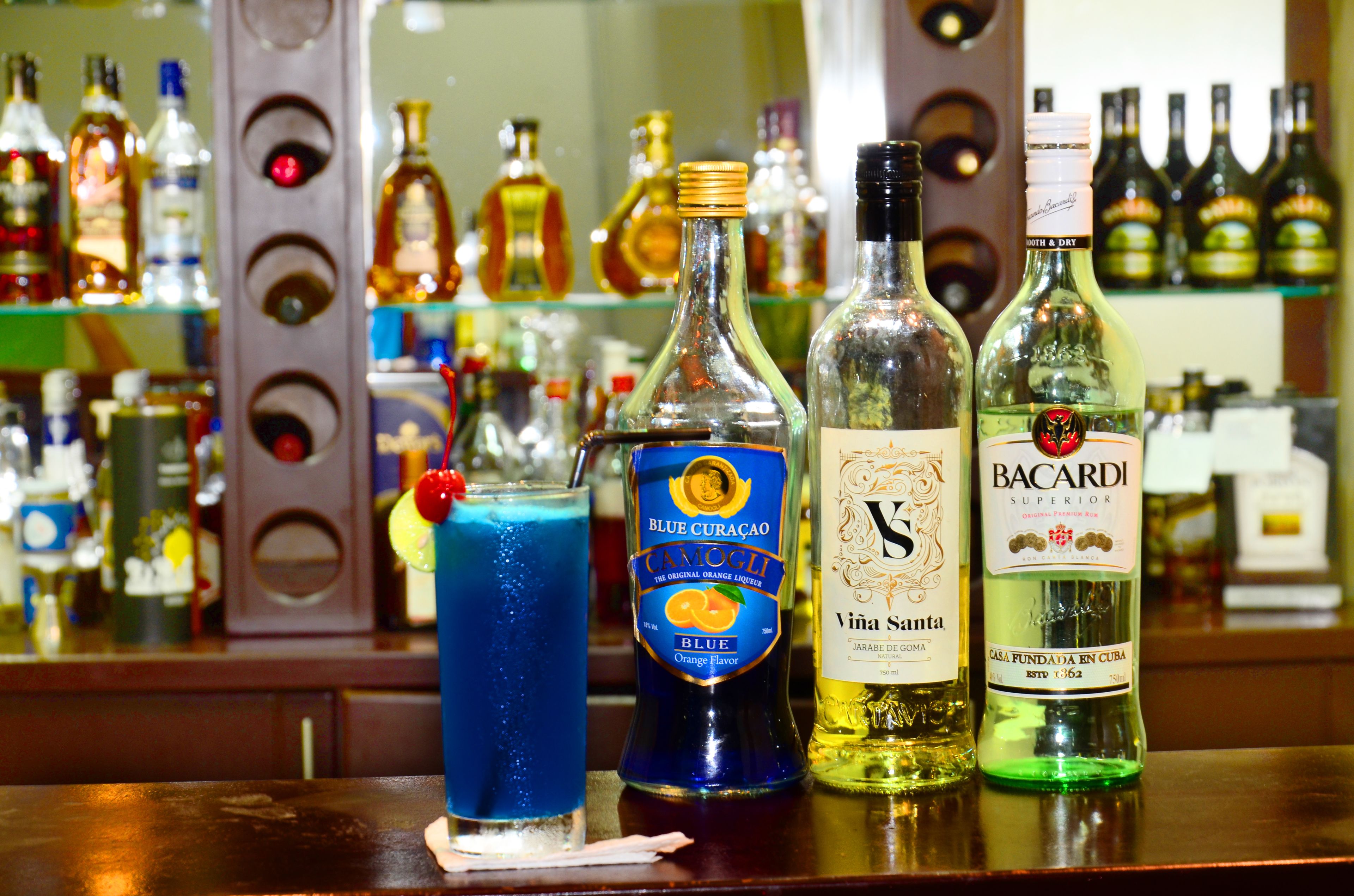 Um balcão com diversas garrafas de bebidas alcoólicas, incluindo Bacardi e Blue Curaçao.