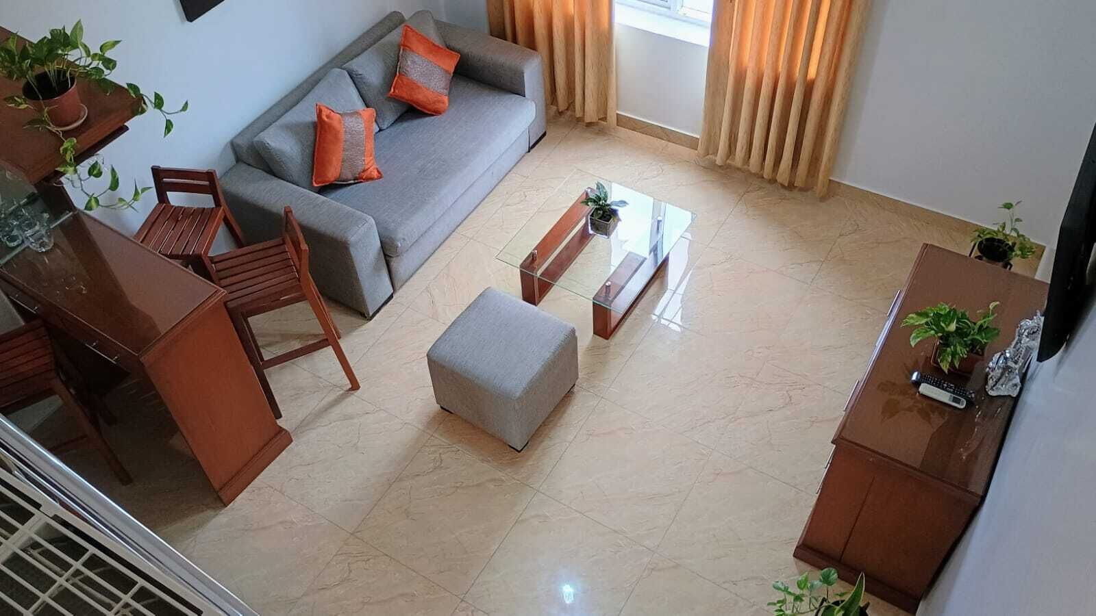 Una sala de estar con sofá, reposapiés, mesa de centro y un comedor con sillas y mesa.