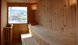 A wooden sauna with a bench, a window, and a view of buildings outside. - Hotel RioSol (Tarapoto)