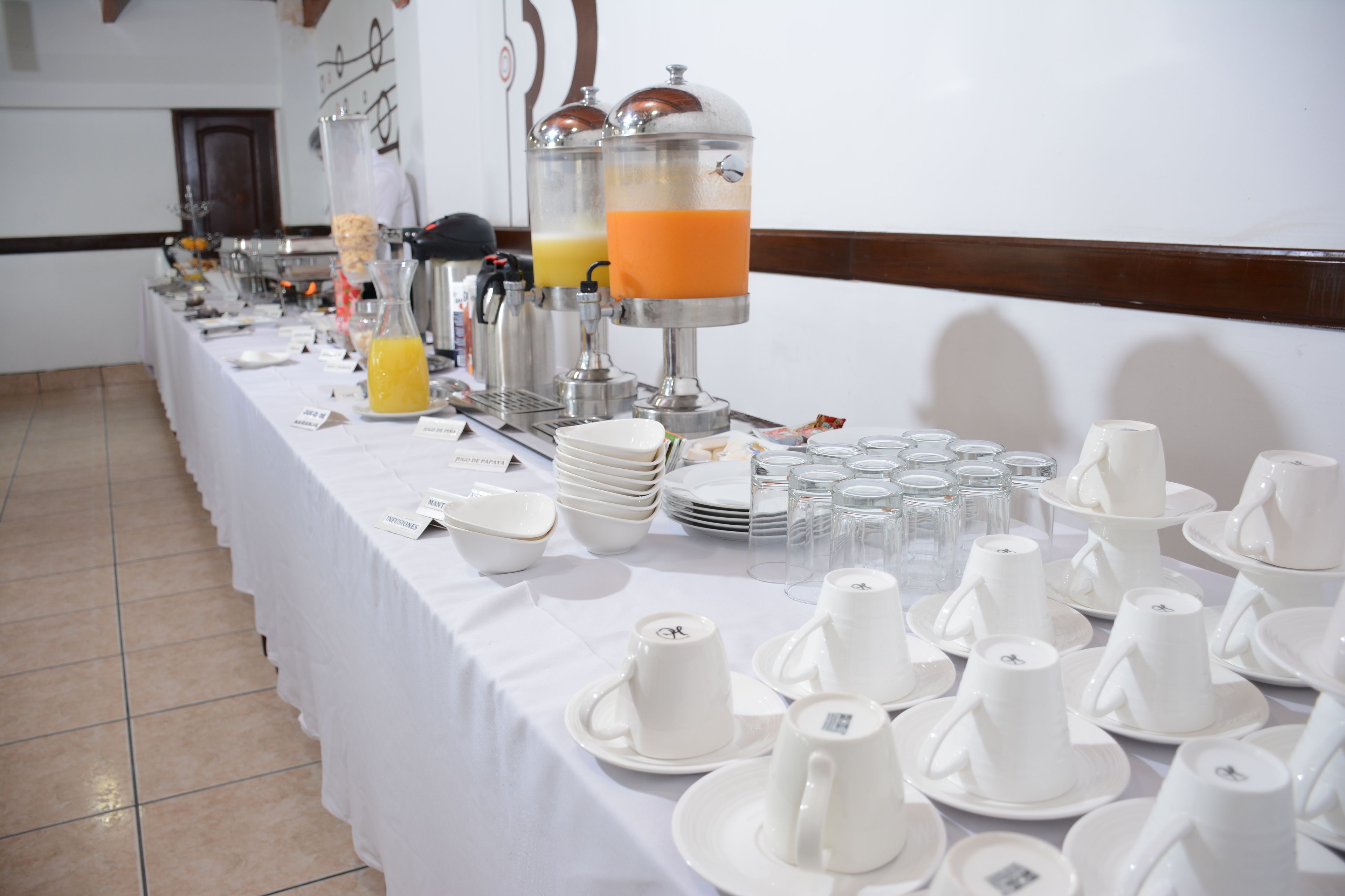 A buffet setup with various food items and beverages, including a juice dispenser and plates.