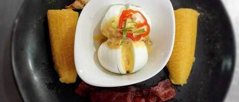 A plate with a boiled egg, bacon, toast, and banana slices.