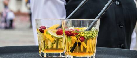 Dos vasos de una bebida con fruta y hierbas sobre una bandeja.