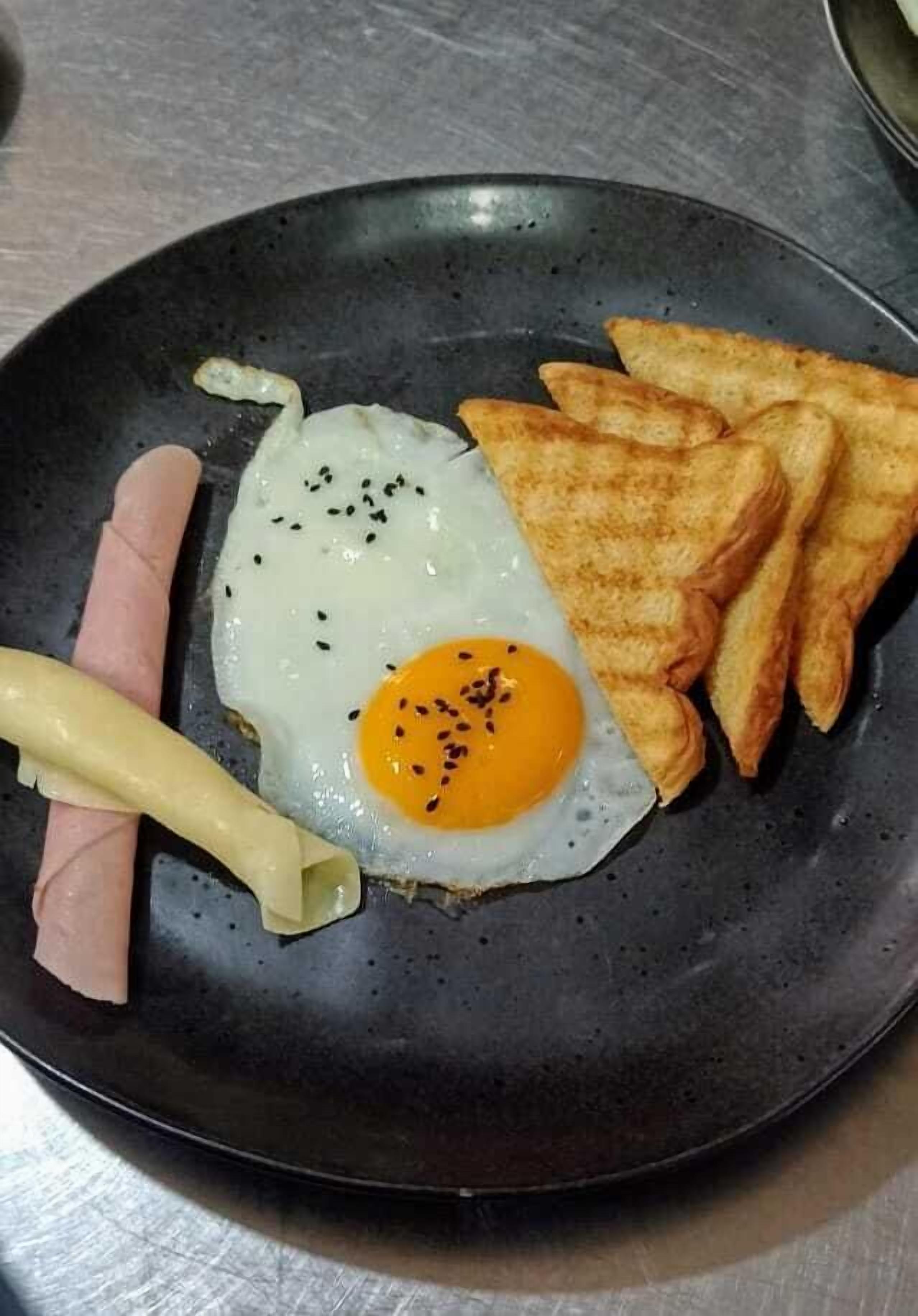 Un plato con un huevo frito, tostada y jamón.
