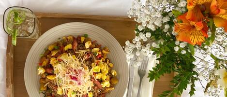A tray with a plate of food, a glass of drink, and a floral arrangement.