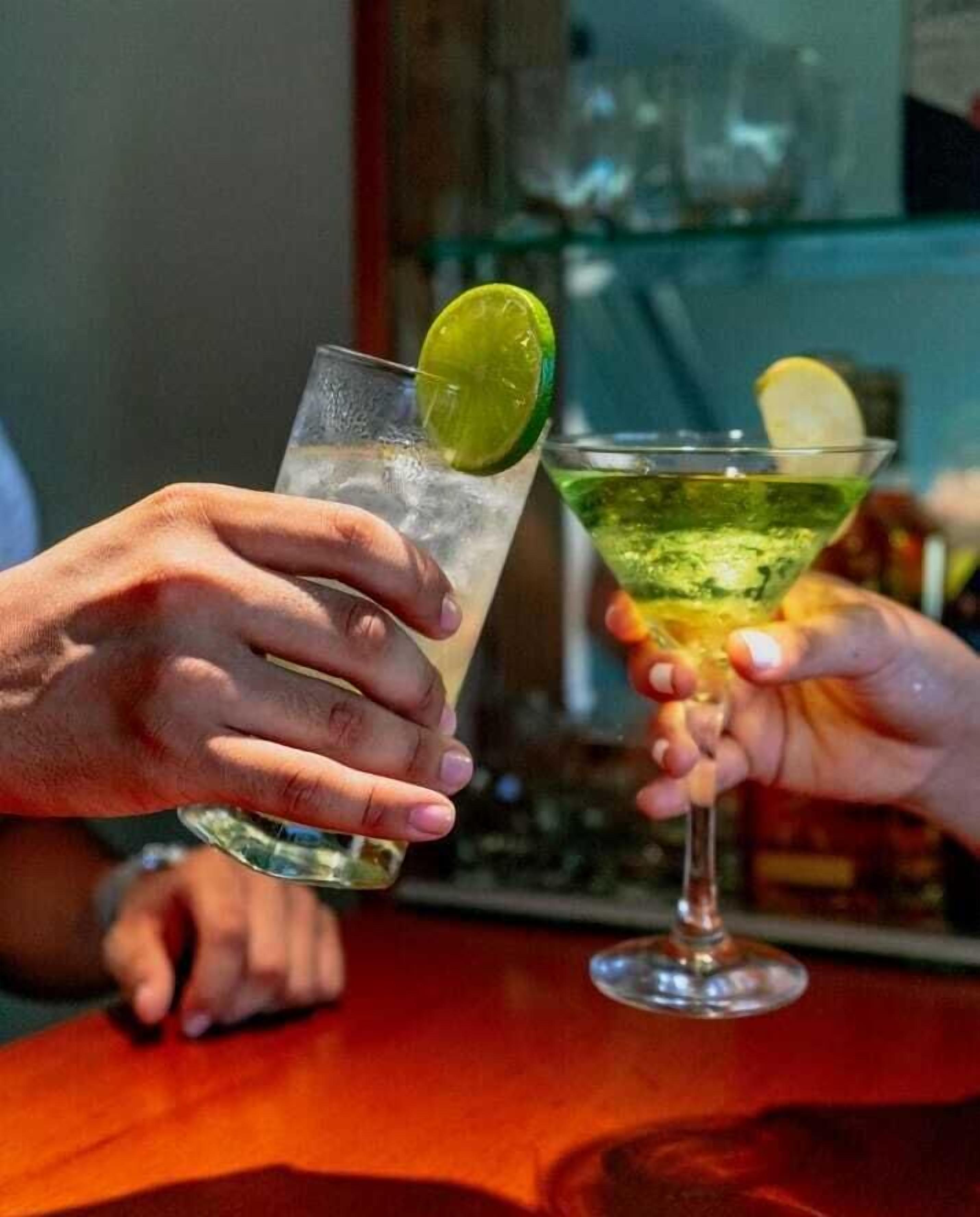 Two people holding drinks at a bar.
