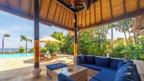 A covered outdoor seating area with a pool, lounge chairs, and a view of the ocean. - 5 * Lovina Beachfront pool villa Free Dolphin Tour (Dencarik)