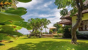 A tropical resort with a thatched-roof building, a pool area with lounge chairs, and lush greenery. - 5 * Lovina Beachfront pool villa Free Dolphin Tour (Dencarik)