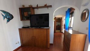 Una sala de estar con un mueble de madera, un televisor de pantalla plana y una decoración de peces en la pared.