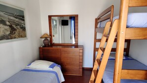 Un dormitorio con dos camas individuales, un aparador de madera, un espejo y un cuadro en la pared.