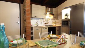 A modern kitchen with a built-in microwave, a stainless steel refrigerator, and a gas stove. - Surrounded by greenery near the sea (Rosa cottage) (SPIGNO SATURNIA)