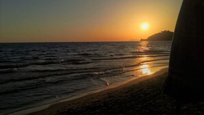 A beach scene with a sunset, waves, and a silhouette of a mountain in the background. - Surrounded by greenery near the sea (Rosa cottage) (SPIGNO SATURNIA)