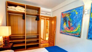 Une chambre d’hôtel avec un lit, une armoire, un tableau et une porte donnant sur une autre pièce.