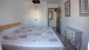 A bedroom with a bed, a dresser, a wardrobe, a mirror, and a hanging light fixture. - The Blue Pearl, a dream terrace in the sun (Roquetas de Mar)