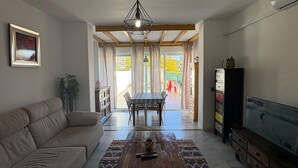 A living room with a sofa, a wooden coffee table, a TV, and a dining area with a table and chairs. - The Blue Pearl, a dream terrace in the sun (Roquetas de Mar)