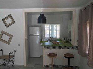 A compact kitchen with a refrigerator, a sink, and a hanging light fixture. - The Blue Pearl, a dream terrace in the sun (Roquetas de Mar)