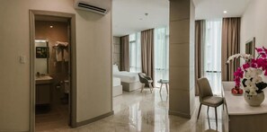 A modern hotel room with a bathroom, a living area with a sofa and chairs, and a dining area with a table and chairs. - TD Central Hotel & Apartment (Ho Chi Minh City)