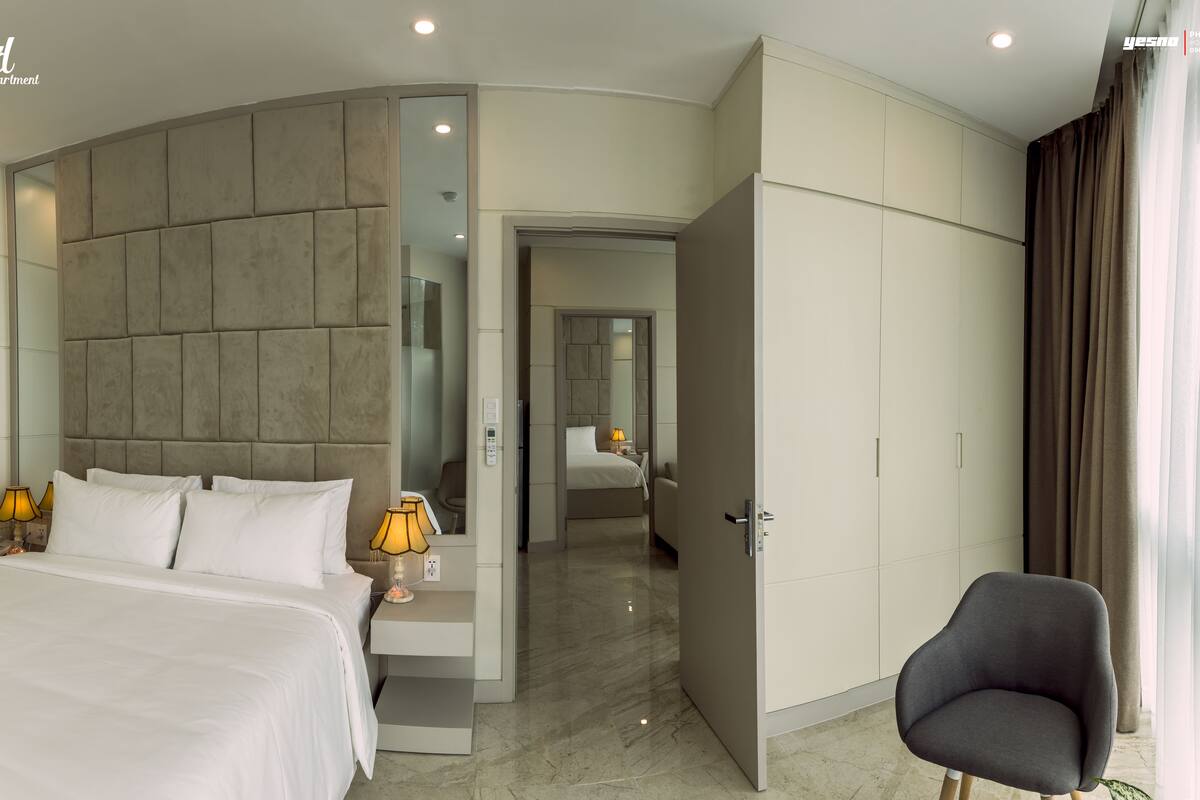 A modern hotel room with a large bed, a seating area, and a bathroom visible through an open door.