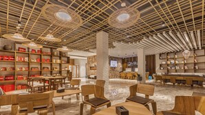 A spacious lobby with a high ceiling, wooden bookshelves, and a stone accent wall. - Purmei Hotel Lugu Lake (Lijiang)