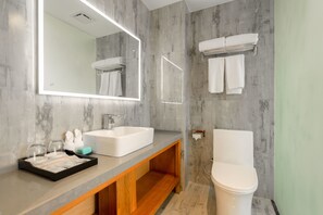Een moderne badkamer met een grote spiegel, een witte wastafel en een toilet.