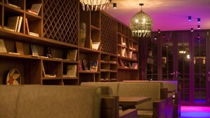 A cozy seating area with wooden bookshelves and a hanging light fixture. - Purmei Hotel Lugu Lake (Lijiang)
