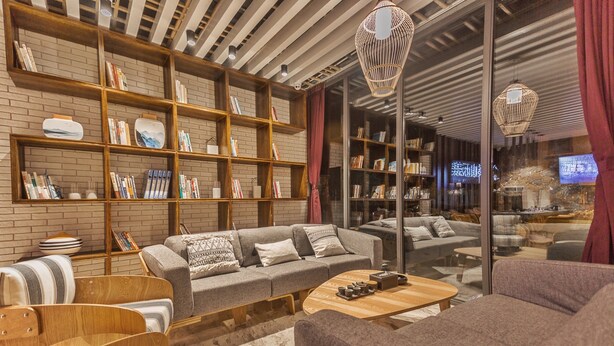 A modern living room with a grey sofa, wooden shelves, and a coffee table. - Purmei Hotel Lugu Lake (Lijiang)