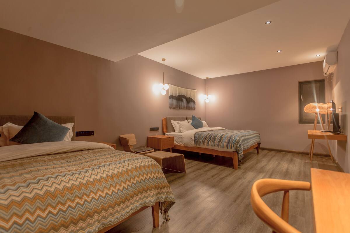 Een moderne hotelkamer met twee bedden, een bureau, een stoel en een wandlamp.