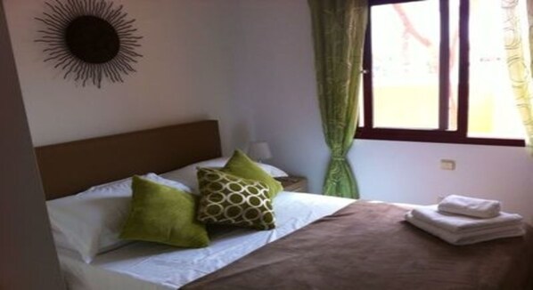 A neatly made bed with a brown headboard, two pillows, and a folded towel on the side.