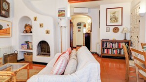Un salon chaleureux avec un canapé, une cheminée, une bibliothèque et un coin repas avec des chaises.