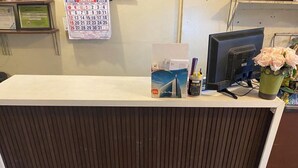 A reception desk with a calendar, a computer monitor, and a vase with flowers. - Pension Inn Marilao (Marilao)