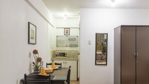 A compact kitchen with a microwave, sink, and a small dining area with chairs and a table. - Pension Inn Marilao (Marilao)