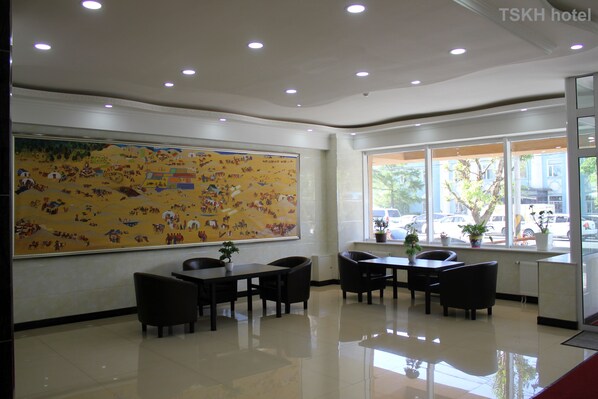 A hotel lobby with a large mural, a reception desk, and a seating area with tables and chairs. - Tsetsen Khangai Hotel (Ulaanbaatar)