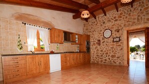 A spacious kitchen with wooden cabinets, a dishwasher, and a stone wall.