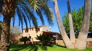 A stone building with a tiled roof, surrounded by palm trees and a well-maintained lawn.