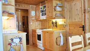 A wooden cabin kitchen with a stove, sink, and various kitchen utensils.